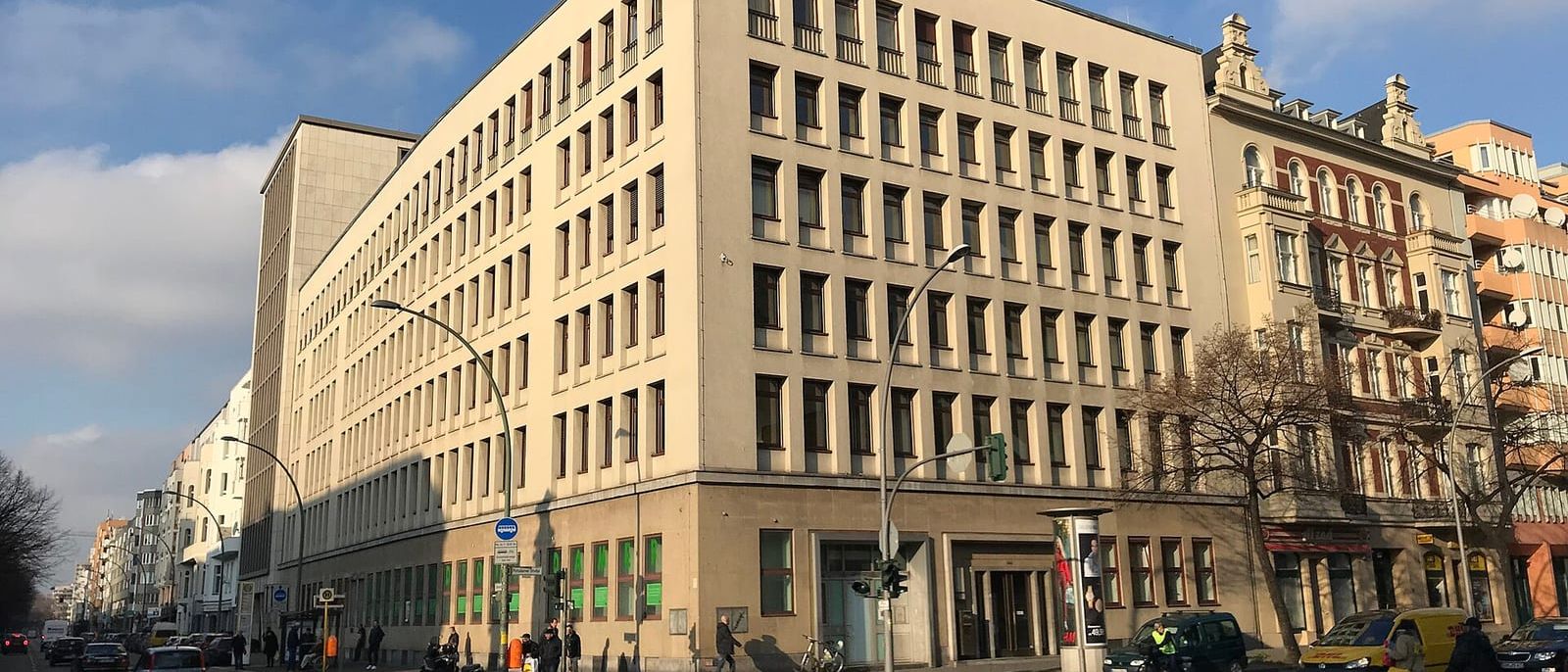 Großes helles Bürogebäude des Finanzamts Schöneberg an einer Straßenkreuzung in Berlin