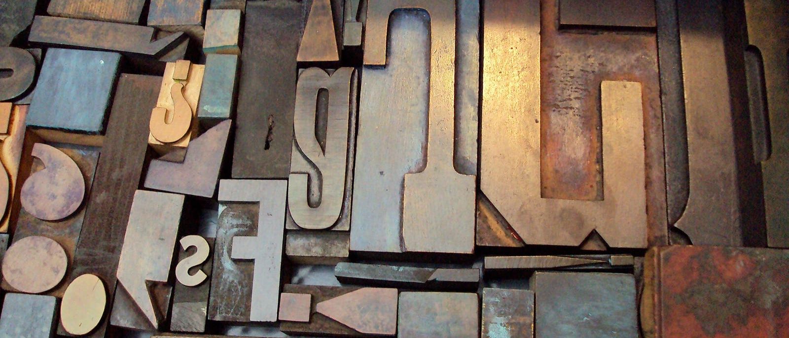 Durcheinanderliegende alte Holzlettern für den Buchdruck in verschiedenen Größen und Farben