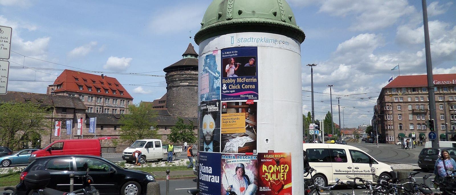 Litfaßsäule mit Konzert- und Theaterplakaten an einem Platz in Nürnberg, davor abgestellte Fahrräder