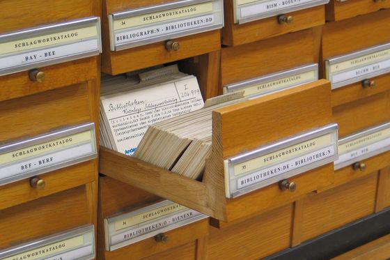 Holzschubladen eines Schlagwortkatalogs in einer Bibliothek, eine Schublade mit Karteikarten ist herausgezogen