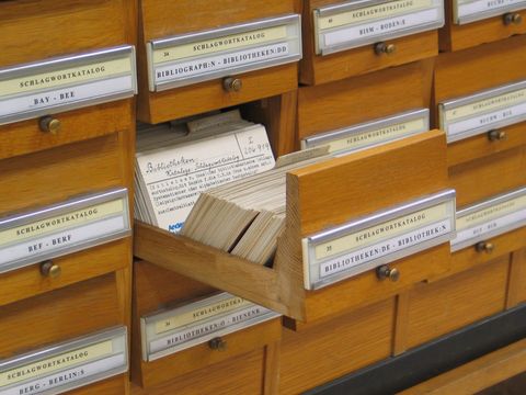 Holzschubladen eines Schlagwortkatalogs in einer Bibliothek, eine Schublade mit Karteikarten ist herausgezogen