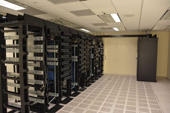 Reihe schwarzer Serverschränke mit blauen Netzwerkkabeln in einem hellen Rechenzentrum
