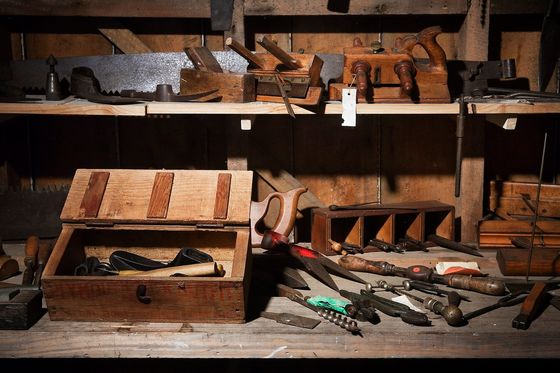 Alte Werkbank mit Hobeln, Sägen, Bohrern und einer offenen Werkzeugkiste aus Holz