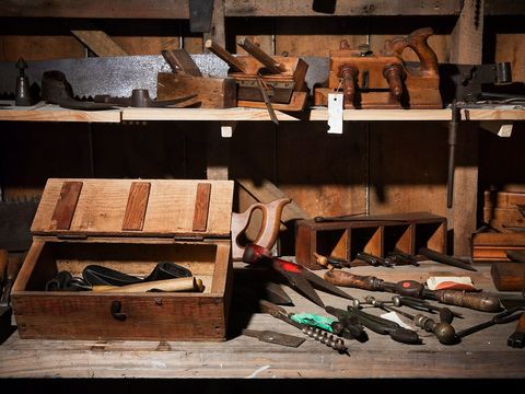 Alte Werkbank mit Hobeln, Sägen, Bohrern und einer offenen Werkzeugkiste aus Holz